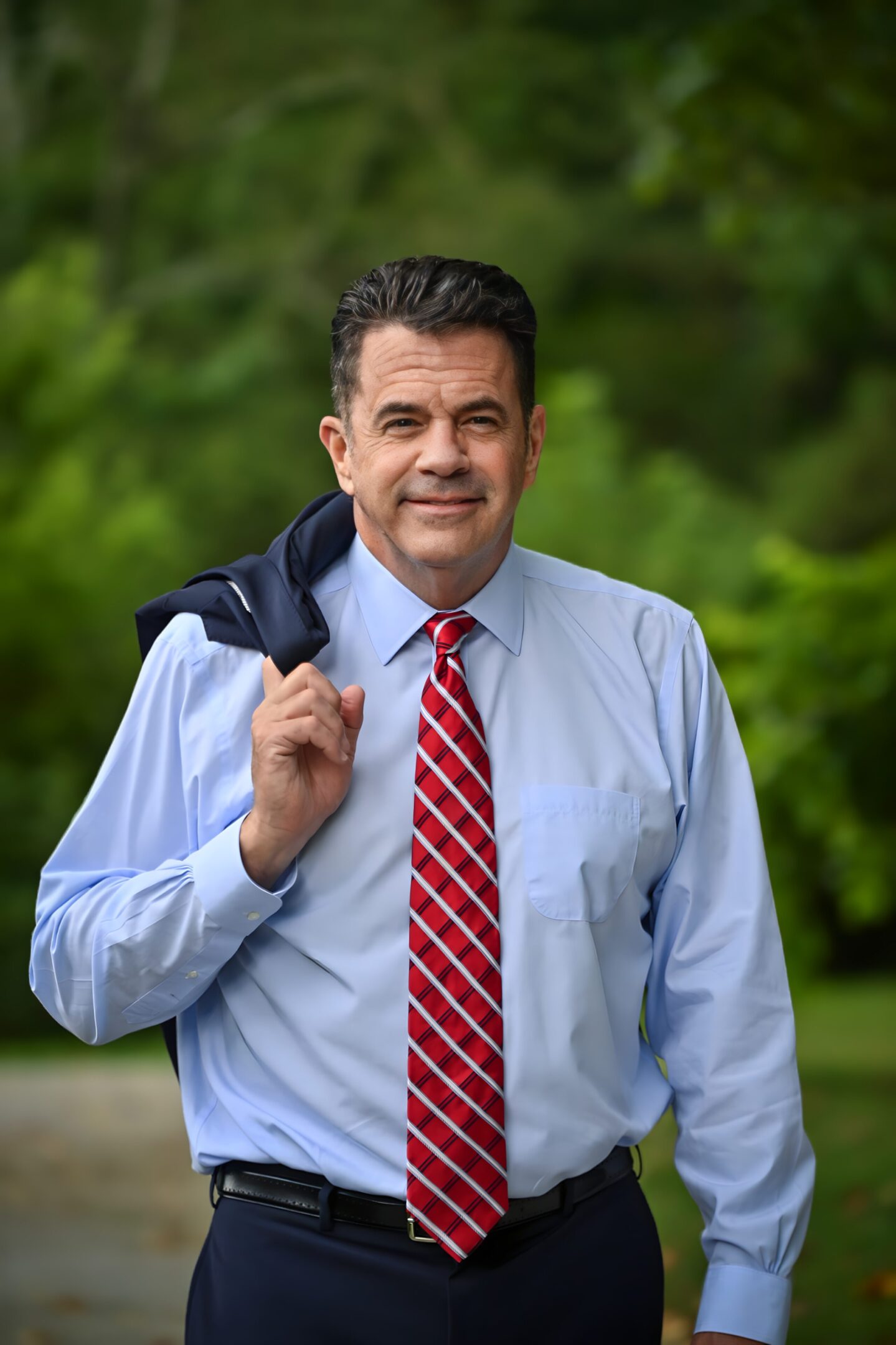 A man in a red tie holding onto his jacket