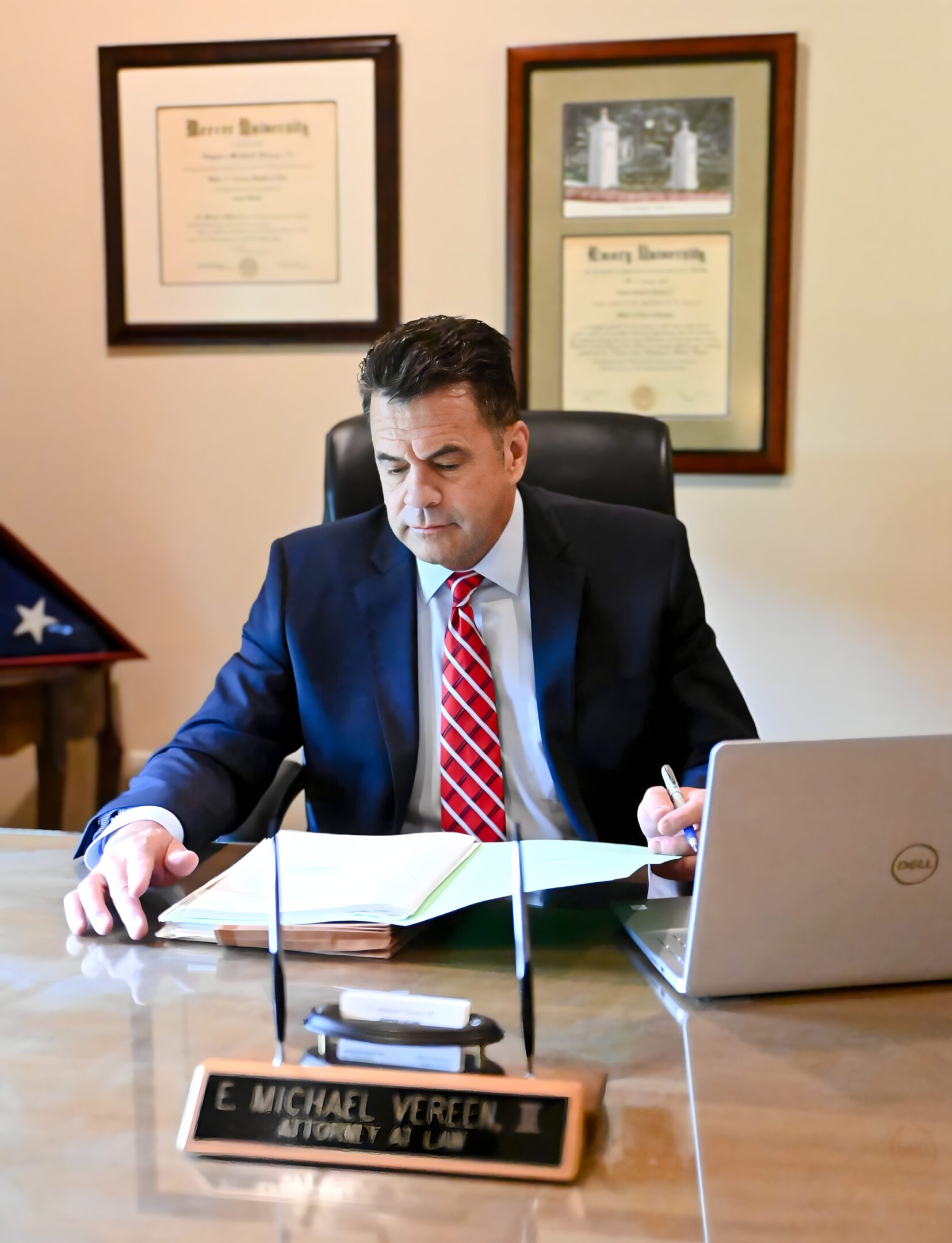 A man sitting at his desk in front of a laptop.